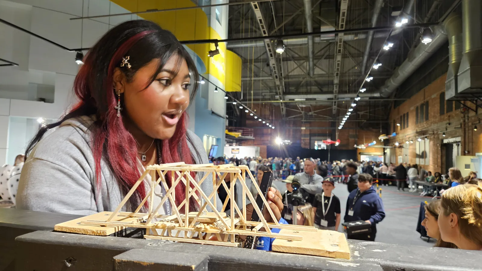 a student reacts as a wooden bridge rests in the testing frame