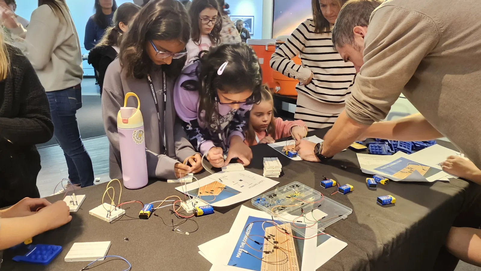 students and a mentor troubleshoot wiring around a crowded worktable